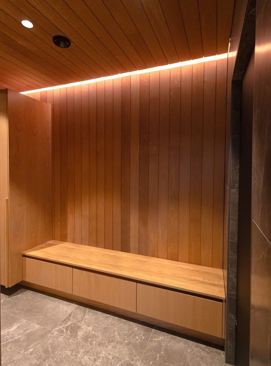 A warm-toned 3 000 Kelvin strip of light in a ceiling-to-wall groove in a wood-panelled changing room.